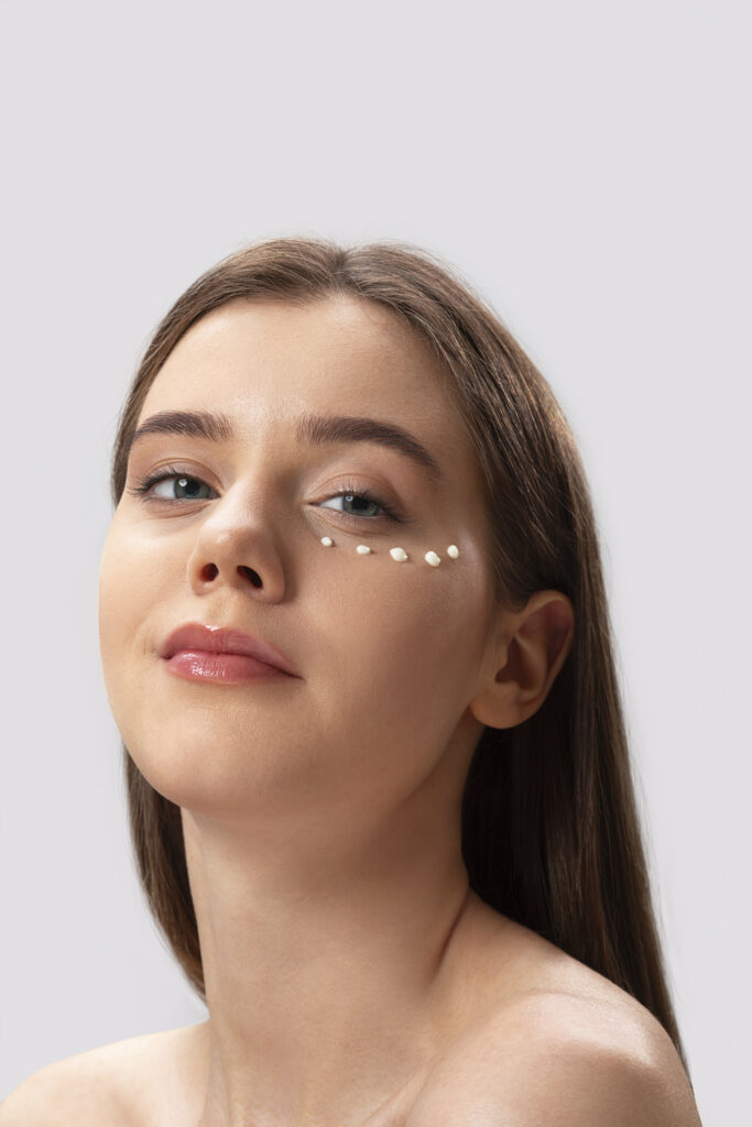 Kobieta z kremem nałożonym punktowo pod oczami.